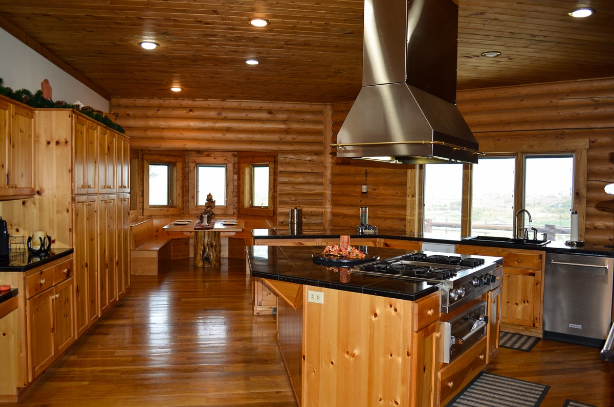 Large kitchen in log home on horse property includes a dining nook.